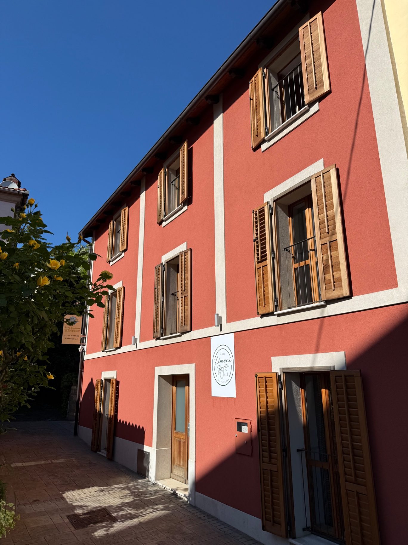 The terracotta facade of Casa Limoni with wooden shutters